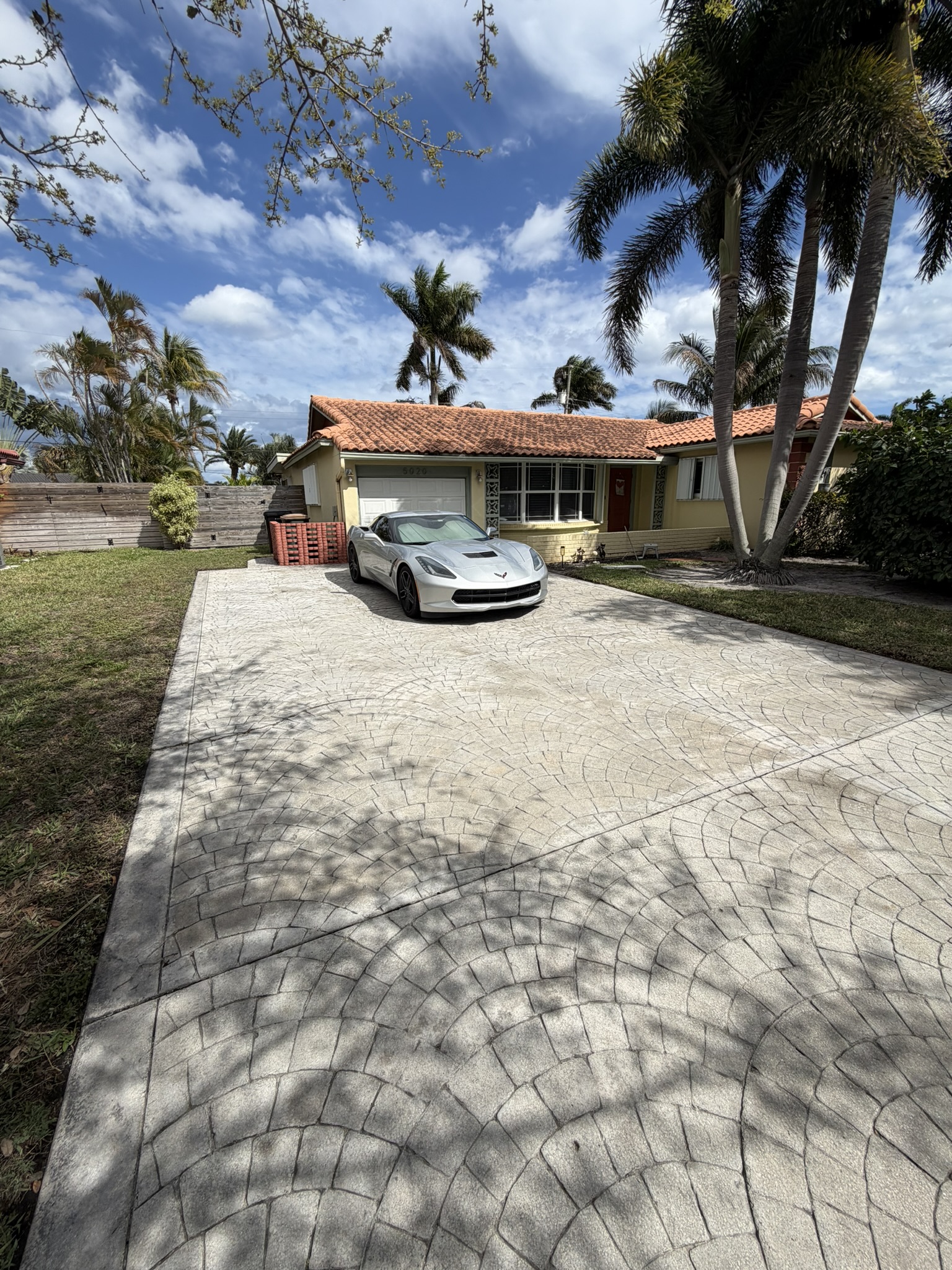 Stamped concrete driveway after Coastal Pressure Pros cleaning — restored pattern and tone, owner's Corvette parked